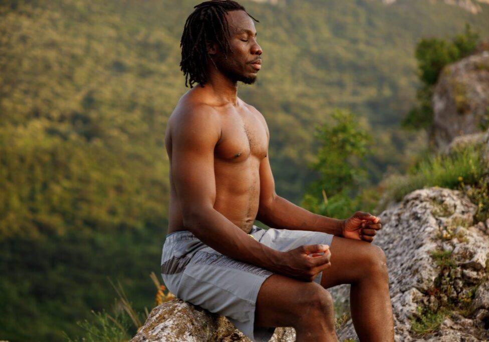 Man meditating on rocky hillside
