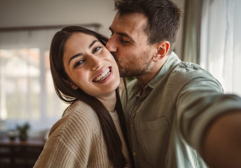 Man kissing woman while taking selfie