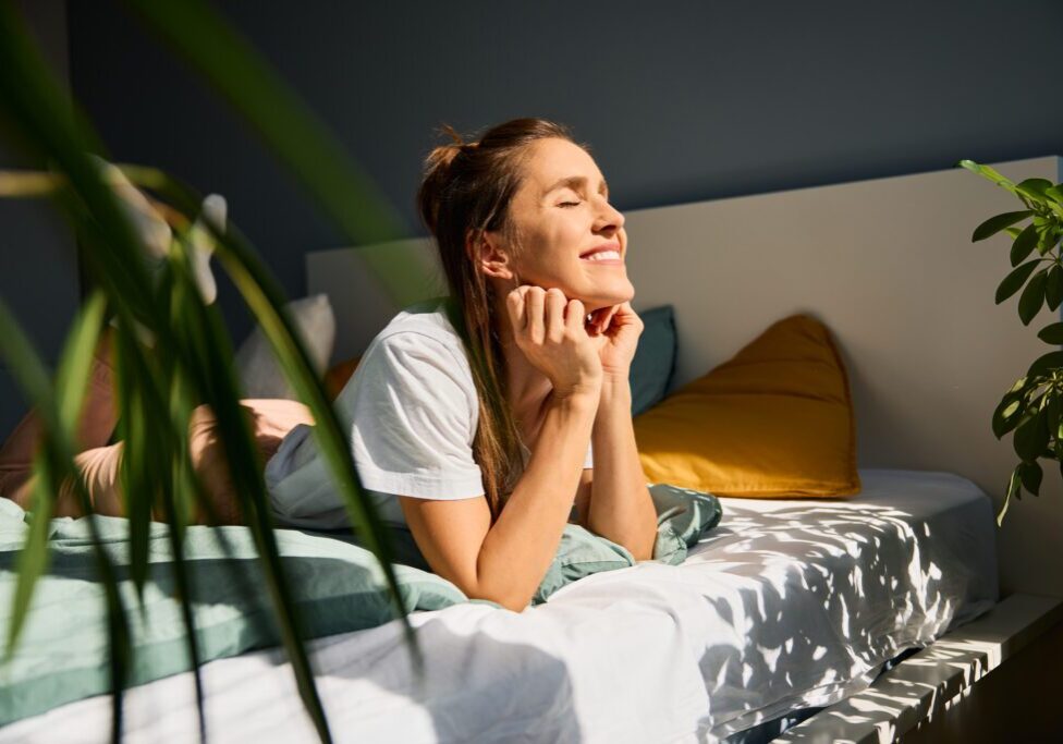 Woman enjoying sunlight in cozy bedroom